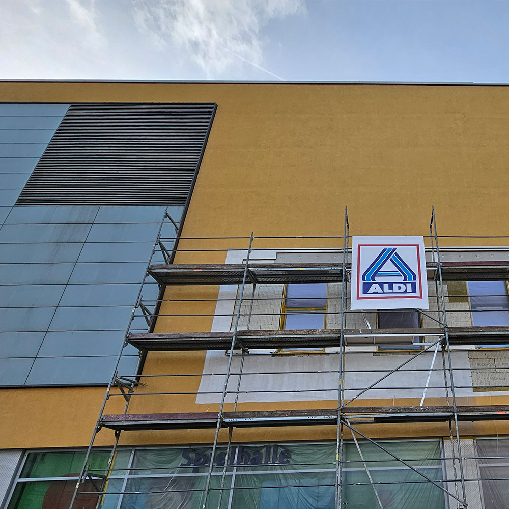 Gebäude mit Gerüst während Fassadensanierung durch Farbenfroh Raumgestaltung.