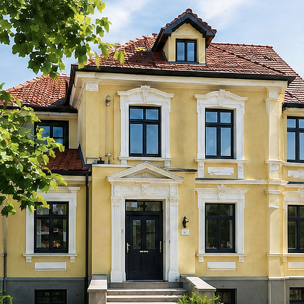 Renoviertes Wohnhaus mit heller Fassade von Farbenfroh Raumgestaltung.