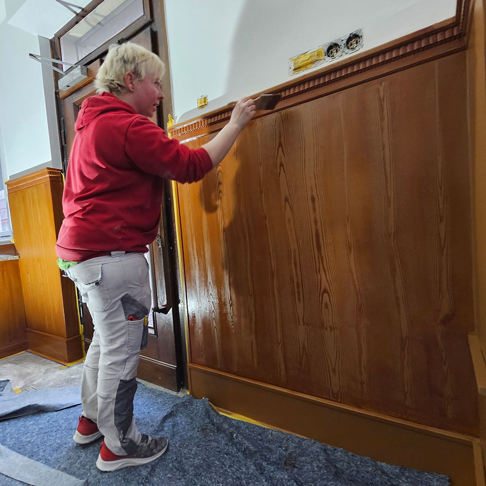 Handwerker bearbeitet Holzverkleidung bei Farbenfroh Raumgestaltung.
